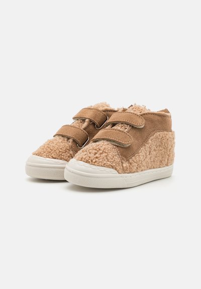 Brown, plush fabric high-top shoes with velcro straps, white rubber soles, and soft texture. Features a lined upper and sturdy stitching.