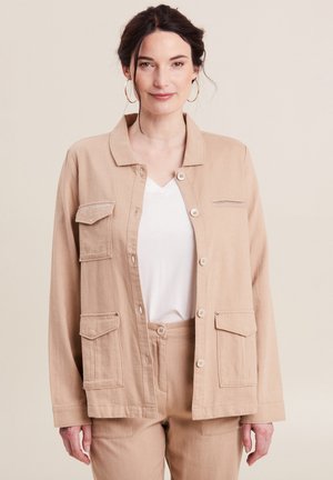 Beige jas met knoopsluiting, twee voorkruiken en een subtiele streepdetaillering op de borst. Lichtgewicht stof, comfortabele pasvorm, gecombineerd met bijpassende broek.