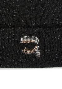 Bonnet en tricot noir en matériau texturé, avec un logo en rhinestones contrastant représentant un visage avec des lunettes de soleil à l'avant.