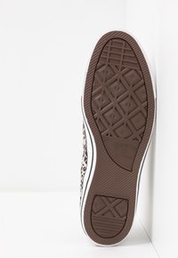 Sola de borracha castanha com padrão de tração geométrica; parte superior em lona com design de estampa de leopardo; detalhes brancos ao longo da sola.