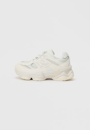 White sneaker featuring a mesh upper with textured accents, a thick rubber sole, and layered design for added support.