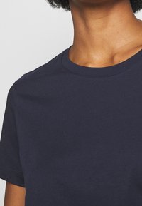 Navy blue cotton t-shirt with a round neckline and short sleeves. Smooth texture, minimal stitching details, and a classic fit.