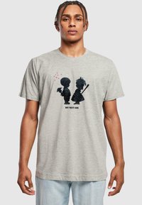 Graues Baumwoll-T-Shirt mit einem grafischen Design von zwei Silhouetten, einem Jungen und einem Mädchen, mit Herzen darüber und dem Text "JUNGE TRIFFT MÄDCHEN" darunter.