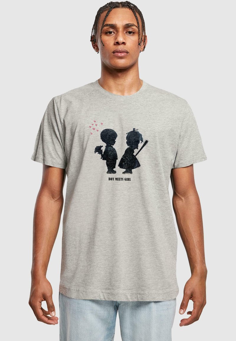 Graues Baumwoll-T-Shirt mit einem grafischen Design von zwei Silhouetten, einem Jungen und einem Mädchen, mit Herzen darüber und dem Text "JUNGE TRIFFT MÄDCHEN" darunter.