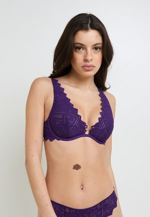 Reggiseno in pizzo viola con bordi ondulati e motivo geometrico, caratterizzato da un design a V e una chiusura decorativa frontale.