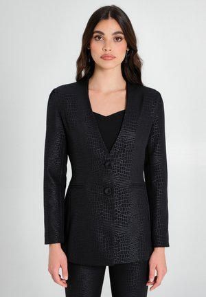 Blazer nero con un motivo a croc testurizzato, chiusura a bottone singolo, design su misura e maniche lunghe, abbinato a un top nero.