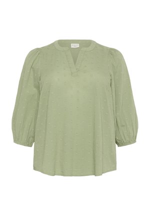 Lichtgroene blouse met een V-hals en pofmouwen. Heeft een geappliceerd stippenpatroon in het hele ontwerp en elastische manchetten. Zachte stof.