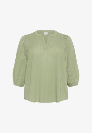 Világos zöld blúz V kivágással és puffos ujjakkal. Az anyag felületét textúrált pöttyös minta díszíti, rugalmas mandzsettákkal. Puha anyag.