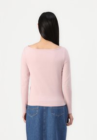 Langermet topp i myk rosa stoff, med vid utrigning og tettsittende design, kombinert med et denimskjørt med to baklommer.