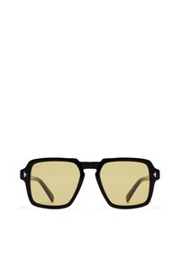 Mustat kulmikkaat aurinkolasit keltaisilla linsseillä, joissa on paksut kehykset ja erottuvat sivukoristeet. Tartuissa on kuvioitu pinta.