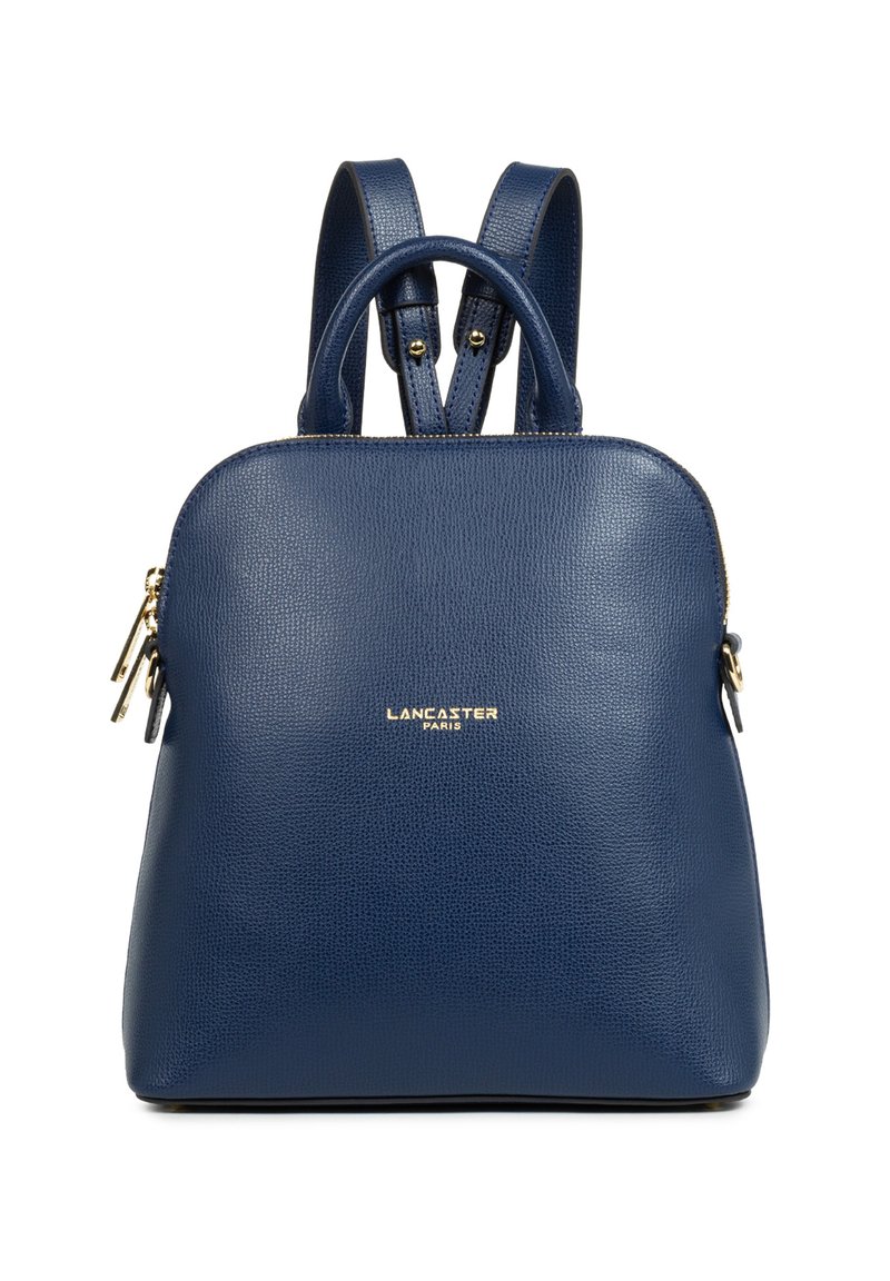 Zaino in pelle blu con superficie testurizzata, forma arrotondata, doppie spalline, manico superiore e un accento logo dorato sul davanti.