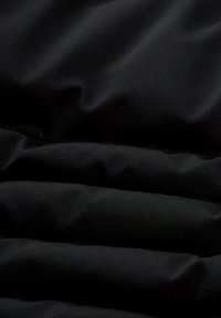 Černá tkanina s matným povrchem, zdobená jemnou texturou a těsně uspořádanými horizontálními sklady. Měkká s mírným leskem.