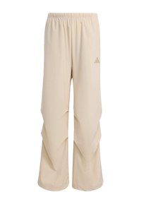 Béžové sportovní kalhoty s volným střihem, elastickým pasem a jemnými vzorovanými akcenty. Na kalhotách je malé logo Adidas v světlé barvě.