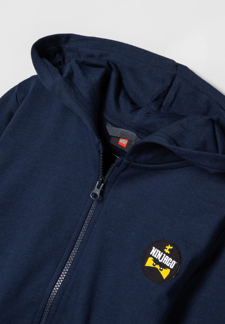Marineblaue Zip-Hoodie mit einem gelben und schwarzen Ninjago-Logo-Patch. Aus weichem Material, mit Kapuze mit Kordelzug und frontalem Reißverschluss.