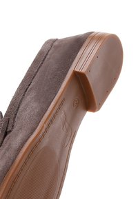 Bruine suède herenloafer gezien vanaf de zool, met een gestructureerde rubberen buitenzool en een lage hak.