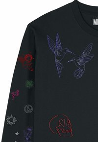 Sweatshirt noir avec des contours de colibri violets sur la poitrine, un crâne rouge aux yeux en forme de cœur, et des motifs colorés sur les manches comprenant un ange, un flamant rose, un signe de paix et un soleil.