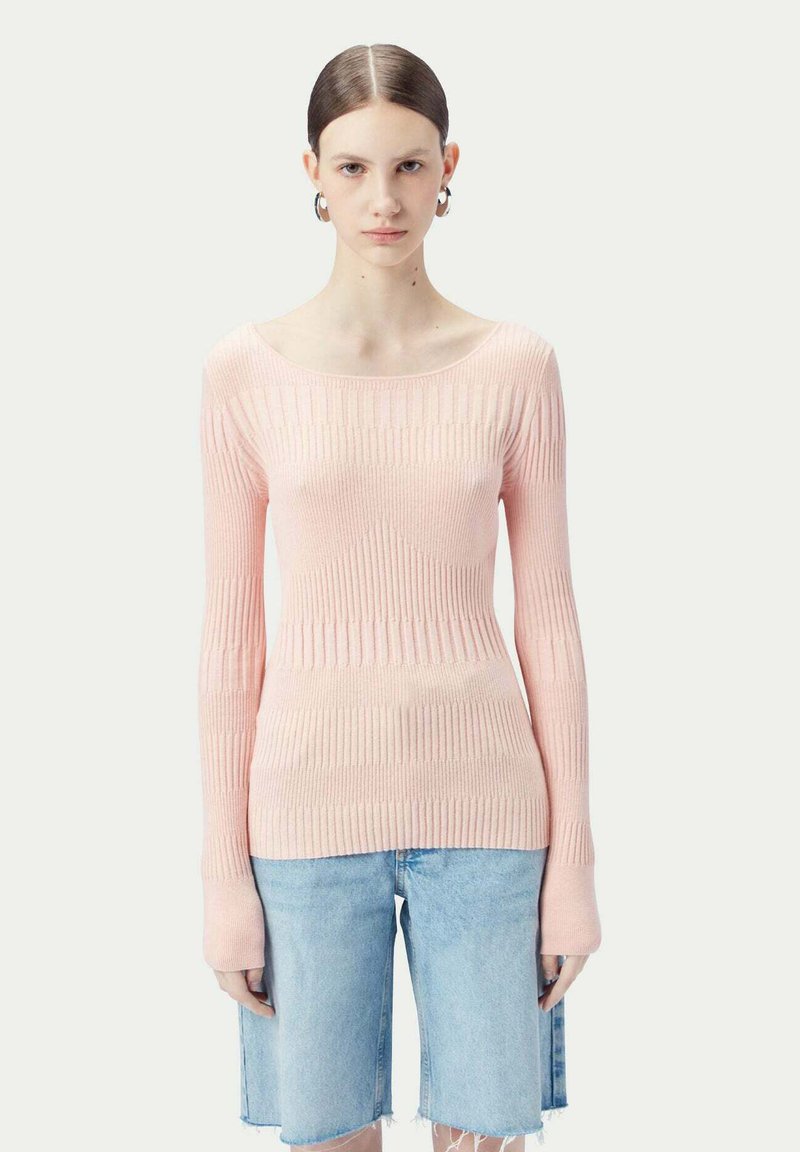 Ljusrosa ribbad stickad tröja med långa ärmar, båtkrage och texturerat mönster. Matchad med denimshorts och enkla accessoarer.