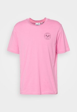 Camiseta rosa de manga corta y cuello redondo con un pequeño logo negro de raqueta de tenis y texto circular en el pecho izquierdo.