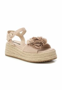 Sandalia de cuña beige con detalle de flor, parte superior de tela, correa ajustable en el tobillo y suela de plataforma envuelta en yute. Suela exterior de goma texturizada.