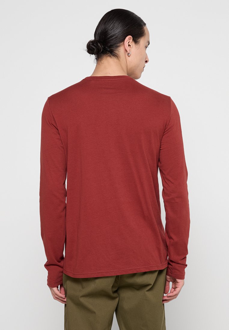 Długi rękaw t-shirt w rdzawoczerwonym kolorze, wykonany z miękkiej bawełny. Oferuje okrągły dekolt oraz dopasowane rękawy, charakteryzując się gładką teksturą i prostym designem.