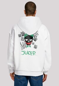 Felpa bianca con un grande grafico del Joker sul retro, con un design di teschio nero e verde e il testo "HA" sparso in bianco e nero.