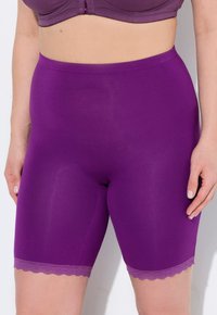 Paarse shorts gemaakt van gladde, stretchy stof met een gegolfde kantafwerking aan de zoom. Het ontwerp heeft een lengte tot halverwege de dij en een nauwe pasvorm.