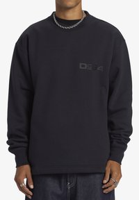 Sudadera negra con cuello redondo, que presenta un sutil logo negro "D94" en el pecho. Confeccionada con una tela suave y texturizada.