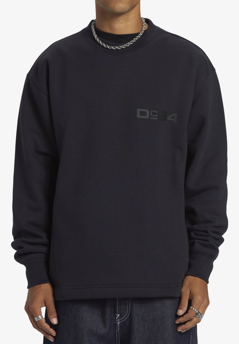 Sudadera negra con cuello redondo, que presenta un sutil logo negro "D94" en el pecho. Confeccionada con una tela suave y texturizada.