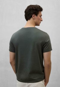 Olivengrøn kortærmet t-shirt med rund halsudskæring; glat stof, afslappet pasform, synlige sømme langs skuldre og ærmer.