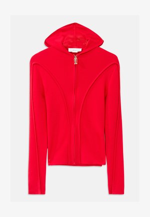 Chaqueta con capucha roja y cierre de cremallera, hecha de un tejido suave, con costuras aerodinámicas, mangas largas y un pequeño detalle de cremallera dorada.