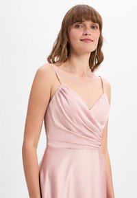 Hellrosa Kleid mit V-Ausschnitt und dünnen Trägern, mit gerafftem Stoff am Oberteil und einem glatten, fließenden Rock.