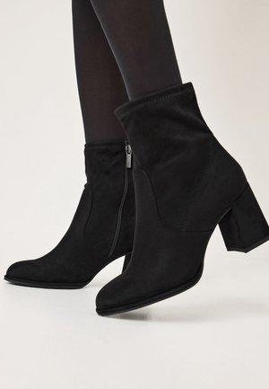Black suede ankle boots with a pointed toe, side zipper, and a block heel. Features a sleek design and smooth texture.