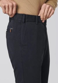 Pantalons bleu marine foncé en tissu doux, à coupe ajustée, avec poches avant et coutures contrastantes. Passants de ceinture présents.