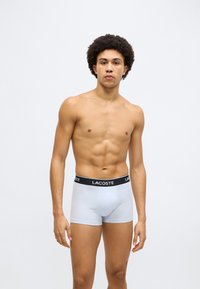 Ανοιχτό μπλε boxer briefs με μαύρη ελαστική ζώνη μέσης με το λογότυπο της Lacoste. Το ύφασμα φαίνεται λείο και ελαστικό, προσφέροντας εφαρμοστή σχεδίαση.