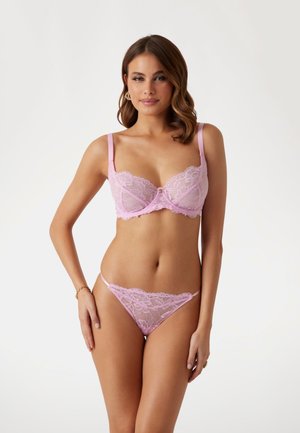 Light pink lace lingerie set with a balconette bra featuring floral patterns and decorative straps, paired with a matching lace thong.