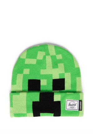 Gorro de punto pixelado verde con ojos y boca cuadrados negros, que se asemeja a un personaje Creeper de Minecraft, con etiquetas de Herschel y Minecraft.