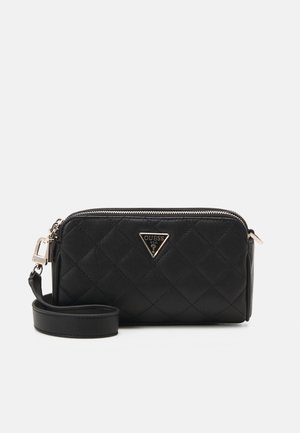 Sac bandoulière noir matelassé avec fermeture éclair sur le dessus et un logo Guess triangulaire argenté à l'avant, doté d'une sangle amovible.