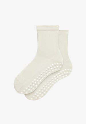Een paar witte enkelsokken met antisliprubbertjes op de zool voor grip en stabiliteit.