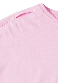 Tissu en coton rose avec une ouverture à l'épaule comportant trois petites attaches cousues en forme de feuille près de l'encolure.