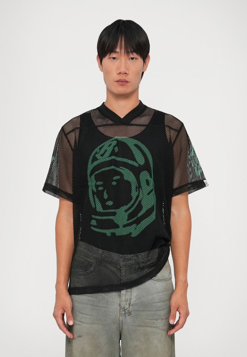 Camisa de malha preta com gráfico de astronauta verde, mangas curtas e design em V. Apresenta uma textura pontilhada e um corte solto.