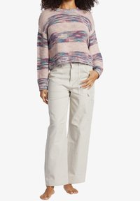 Virkatusta neulepaidasta pastelliväreissä pitkähihaisena, yhdistettynä korkeavyötäröisiin, leveälahkeisiin beigen sävyisiin cargo-housuihin, joissa on sivutaskut.