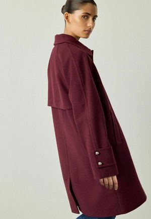 Bordeaux wollen blend jas met een notch-kraag, zijzakken en zilveren knoopaccenten op de manchetten. Heeft een licht oversized pasvorm en een achterkantventilatie.