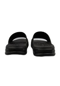 Infradito neri in materiale gommoso liscia, design aperto, plantare testurizzato e branding discreto sul lato.