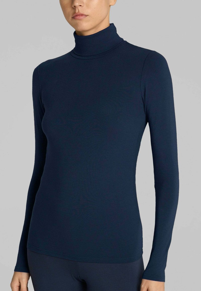 Maglia a collo alto navy realizzata in tessuto liscio e elastico. Maniche lunghe con un design aderente e un colletto alto discreto. Dettagli delle cuciture sull'orlo.