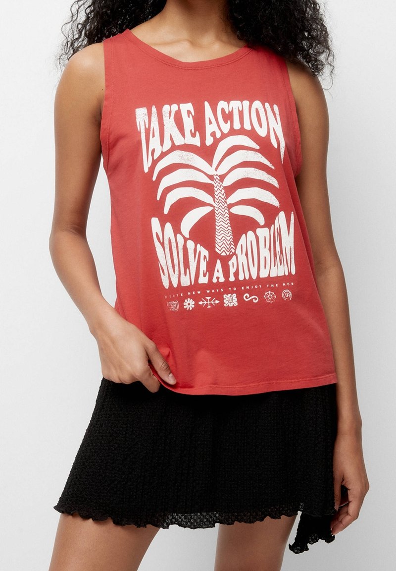 Rød ærmeløs tanktop med hvidt tekstgrafik og palmetrædesign, kombineret med en sort mini-nederdel med tekstur og bølget kant.