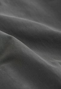 Tissu gris foncé lisse avec des plis doux et fluides et une texture finement tissée.