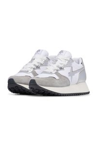 Sneaker bianche e grigie con tomaia in suede e rete, dettagli metallici, lacci piatti, suola in gomma spessa e un design con tacco leggermente elevato.