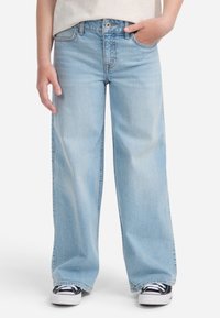 Jeans a gamba larga di un blu chiaro, realizzati in denim, con chiusura a bottoni e zip, cinque tasche e cuciture visibili su tutta la superficie.