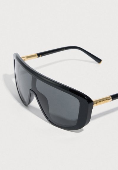 Fekete, túlméretezett napszemüveg sima, tükröződő lencsével és aranyszínű díszítésekkel a szárakon, modern, szögletes kialakítással.