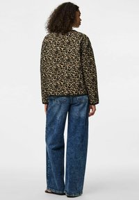 Leopardmönstrad jacka i beige och svart, med långa ärmar och avslappnad passform, kombinerad med lösa blå denimjeans.